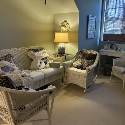 Sale Photo Thumbnail #108: White wicker living room set including a sofa, rocking chair, armchairs, and side table, paired with a white wooden writing desk in the background.