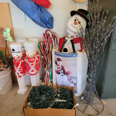 Sale Photo Thumbnail #182: plastic toy soldier blow molds, candy cane pathway markers, a box of green-wire string lights, a lighted wire tree, and an animated singing snowman in its original box.