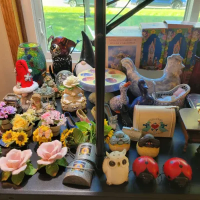 Sale Photo Thumbnail #30: Ceramic flowers, animal figurines, a miniature piano, and holiday-themed items.