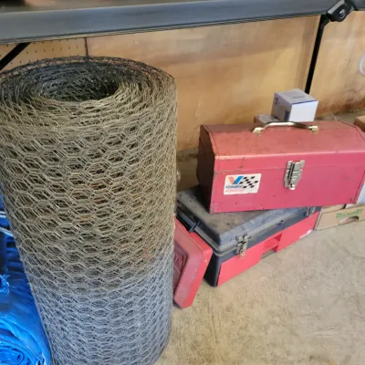 Sale Photo Thumbnail #193: Roll of chicken wire fencing alongside a vintage red metal Valvoline toolbox and other workshop supplies.