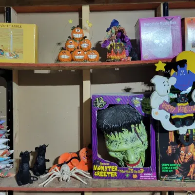 Sale Photo Thumbnail #163: Assortment of vintage Halloween decorations and novelties, including a boxed Frankenstein Monster Greeter, a Crypt Keeper candle, and various pumpkin-themed items.