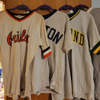 Sale Photo Thumbnail #112: Four vintage MLB baseball jerseys, including Baltimore Orioles, Boston Red Sox, and Oakland Athletics styles.
