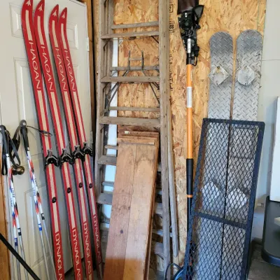 Sale Photo Thumbnail #195: Assorted garage items including vintage Hagan Dynaglas skis, ski poles, a wooden ladder, a pole saw, and metal ramps.