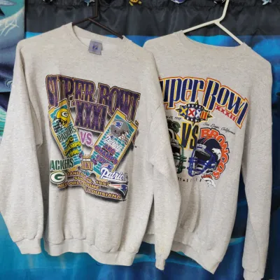 Sale Photo Thumbnail #91: Two vintage grey crewneck sweatshirts featuring Super Bowl XXXI (1997) and Super Bowl XXXII (1998) graphic designs.
