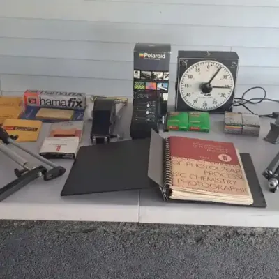 Vintage darkroom and photography equipment, including a Time-O-Lite timer, tripods, a Polaroid 35mm AutoProcessor, and a "Basic...