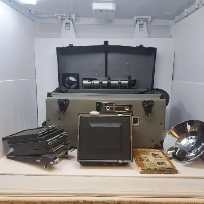 Vintage Graflex Speed Graphic press camera outfit, including the camera body, a hard carrying case, film holders, a flash reflector, and...