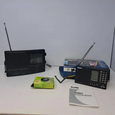 Two portable shortwave radios, including an Info-Mate World Band Radio and a Kaito KA1102 with its original box and operating manual.