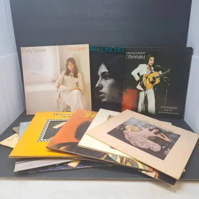 Collection of vintage 1970s vinyl records, featuring albums by Carly Simon, Paul Simon, and Harry Chapin.