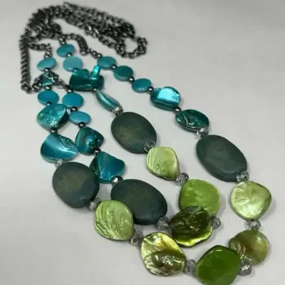 Multi-strand statement necklace featuring a gradient of turquoise, teal, and lime green mother-of-pearl shell pieces and matte beads on a...