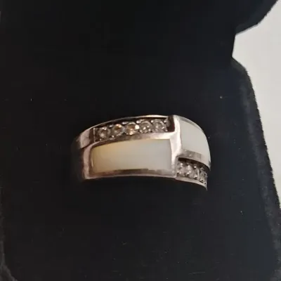 Sterling silver band ring featuring mother-of-pearl inlay panels accented by rows of small cubic zirconia stones, presented in a black...