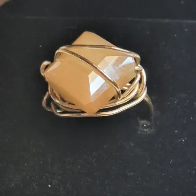 Handcrafted wire-wrapped ring featuring a faceted, square-cut light brown gemstone, presented in a black velvet jewelry box.