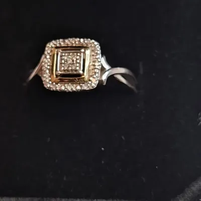 Two-tone sterling silver and gold-plated ring featuring a square halo setting with small diamond accents, presented in a black velvet...