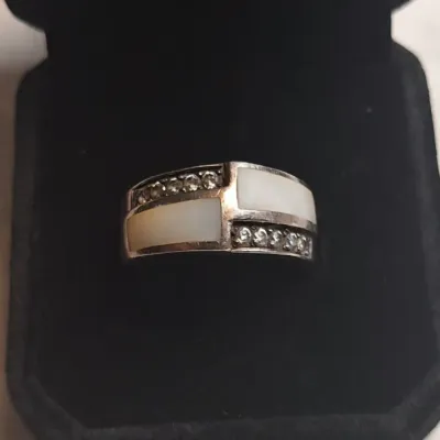 Sterling silver band ring featuring mother of pearl inlay panels accented by rows of small round-cut clear stones, presented in a black...