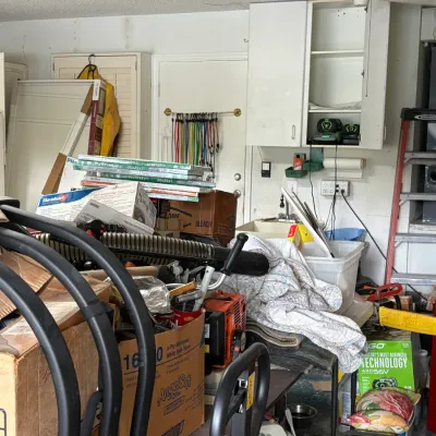 Assorted garage items, including a Werner step ladder, cardboard boxes, various tools, and household supplies.