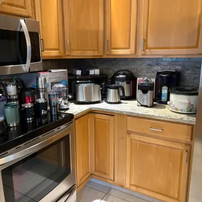 Assorted kitchen small appliances including a toaster, slow cooker, coffee maker, and food processor arranged on a granite countertop...