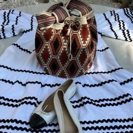 Bohemian-style outfit featuring a white tiered dress with black rickrack trim, paired with a woven geometric bucket bag and white cap-toe...