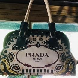 Vintage Prada Milano canvas and leather handbag featuring a graphic logo print, studded black leather trim, and braided rope handles....