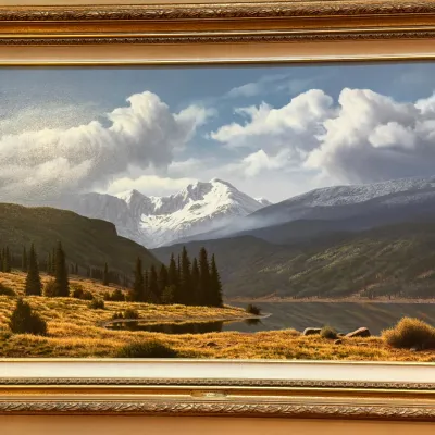 Sale Photo Thumbnail #12: Framed landscape print depicting a snow-capped mountain peak rising above a forested lake, housed in an ornate gold-finished frame 