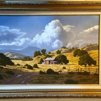 Sale Photo Thumbnail #13: Framed landscape painting depicting a rustic barn in a golden valley under a dramatic cloudy sky, housed in an ornate gilt frame 
