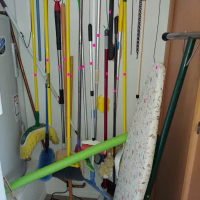 Sale Photo Thumbnail #21: Assortment of household cleaning tools including brooms, mops, and a floral-patterned ironing board.