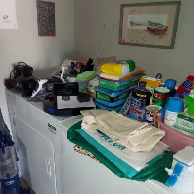 Sale Photo Thumbnail #10: Assorted household items, cleaning supplies, and small appliances, including a Rowenta steam iron, a Shark upright vacuum, and a Eufy robotic vacuum, displayed on top of a white washer and dryer set.