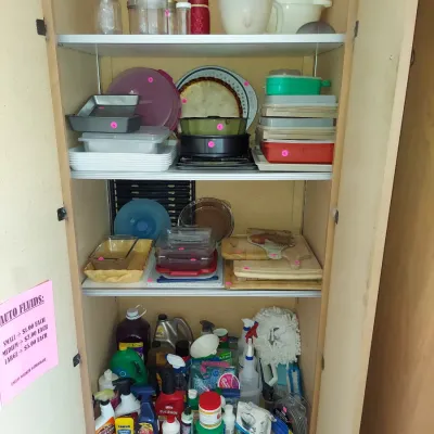 Sale Photo Thumbnail #22: Tall wooden storage cabinet filled with kitchenware, baking dishes, and household cleaning supplies.