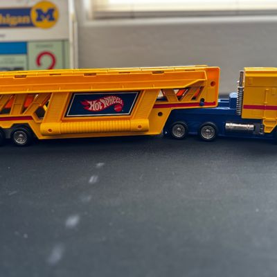 Sale Photo Thumbnail #34: Vintage Hot Wheels car carrier semi-truck toy, featuring a yellow and blue plastic cab with a matching yellow double-decker trailer.