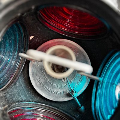 Sale Photo Thumbnail #19: Interior view of a vintage Adams & Westlake railroad switch lamp, showing the burner assembly surrounded by red and blue glass lenses.