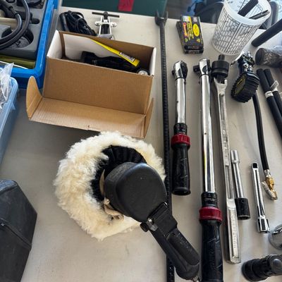 Assorted automotive tools, including a pneumatic buffer with a wool pad, Craftsman torque wrenches, and socket extensions, displayed on a...
