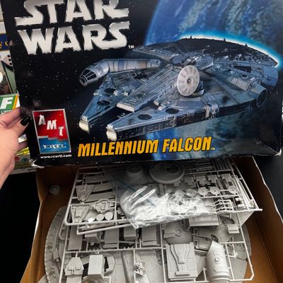 Sale Photo Thumbnail #53: Vintage AMT Ertl Star Wars Millennium Falcon plastic model kit, shown open with unbuilt grey plastic parts on sprues inside the original box.