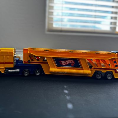 Sale Photo Thumbnail #31: Vintage Hot Wheels yellow and blue car carrier semi-truck toy, showing some light wear from play.