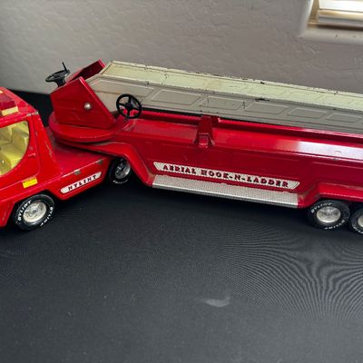 Sale Photo Thumbnail #12: Vintage Nylint pressed steel Aerial Hook-N-Ladder fire truck toy, showing some paint wear and play-worn condition.