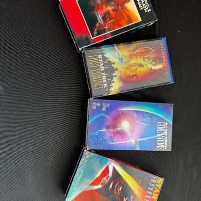 Sale Photo Thumbnail #20: Four Star Trek VHS tapes, including The Wrath of Khan, First Contact, Generations, and Insurrection, showing some wear on the cardboard sleeves.