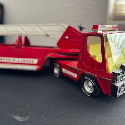 Sale Photo Thumbnail #13: Vintage Nylint pressed steel hook and ladder fire truck, showing some paint wear and a cracked windshield consistent with age.