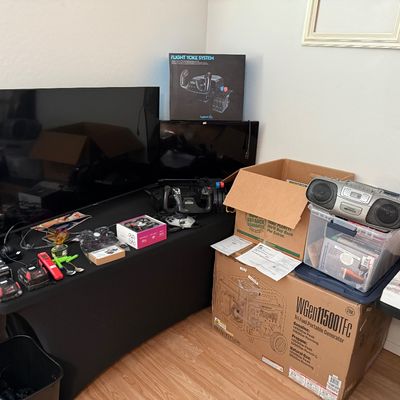 Collection of electronics and household items including flat-screen televisions, a Logitech Flight Yoke System in box, a Westinghouse...