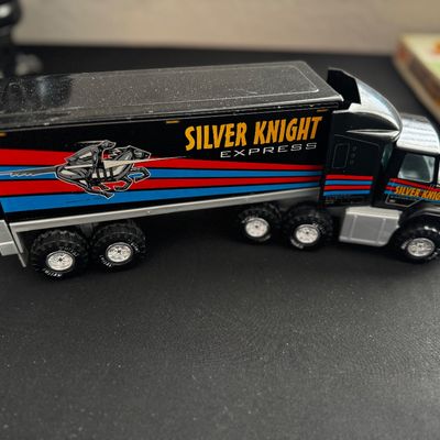 Sale Photo Thumbnail #26: Vintage Nylint Silver Knight Express semi-truck toy, featuring a black cab and trailer with red and blue stripes and knight graphic.