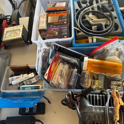 Assorted garage and workshop items, including boxes of drywall screws, a vacuum pump kit, various electrical components, and power adapters.