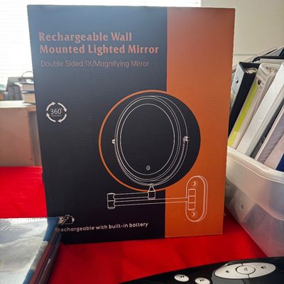 Rechargeable wall-mounted lighted mirror in its original packaging, featuring a double-sided 1X and magnifying design with a 360-degree...