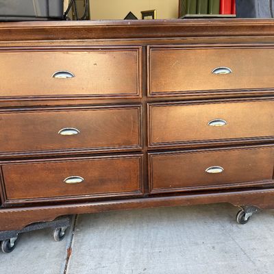 Traditional dark wood six-drawer dresser featuring silver cup drawer pulls and molded trim details.