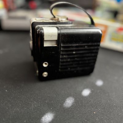 Sale Photo Thumbnail #64: Vintage black plastic pocket radio with a carrying strap, showing some wear from age and use.