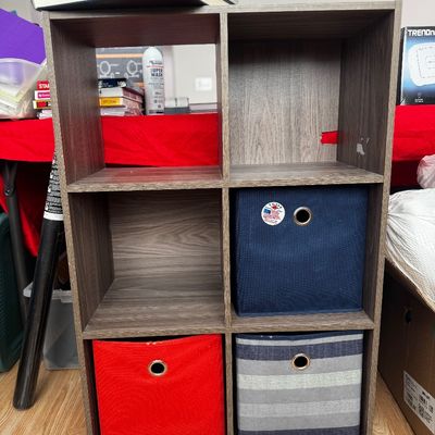 Six-cube laminate organizer shelf in a gray woodgrain finish, featuring three fabric storage bins in red, navy blue, and striped patterns.