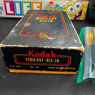 Sale Photo Thumbnail #69: Vintage Kodak Vigilant Six-20 camera box, showing some edge wear and scuffing, with a SpongeBob SquarePants Game of Life box visible in the background.