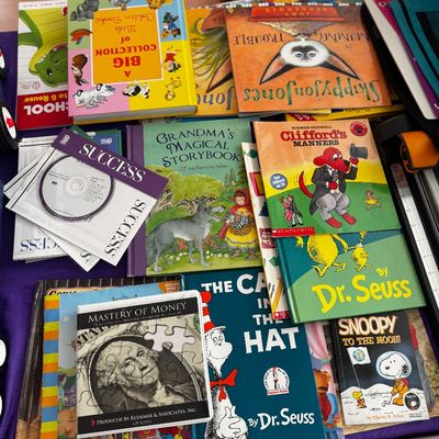 Assortment of children's books and educational media, including titles by Dr. Seuss, Clifford the Big Red Dog, and Snoopy, alongside...