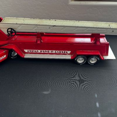Sale Photo Thumbnail #11: Vintage Nylint Aerial Hook-N-Ladder pressed steel toy fire truck trailer, showing some paint wear and age-appropriate patina.