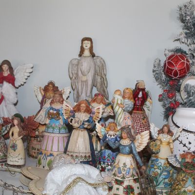 Collection of Jim Shore Heartwood Creek angel figurines in various sizes and designs, displayed alongside Christmas decor.