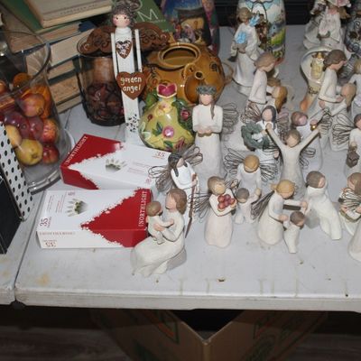 Collection of Willow Tree style angel and family figurines, displayed alongside decorative signs, a glass jar of faux fruit, and boxed...