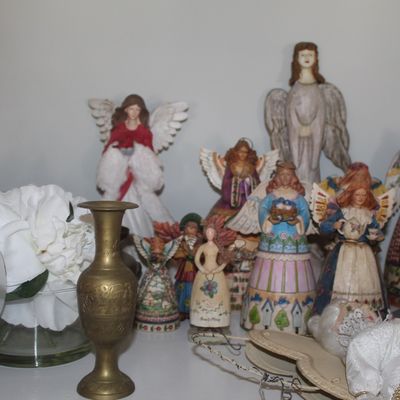 Collection of Jim Shore Heartwood Creek angel figurines in various sizes and designs, displayed alongside a vintage-style white alarm...
