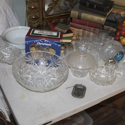 Assortment of vintage glassware, including cut glass bowls, a lidded candy dish, and drinking glasses, displayed alongside books and...