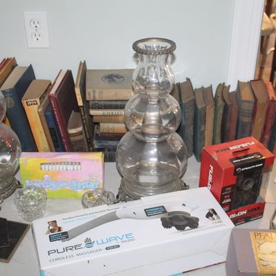 Pair of vintage clear glass hurricane lamp bases with ornate metal trim, displayed alongside a collection of old books, a Pure Wave...
