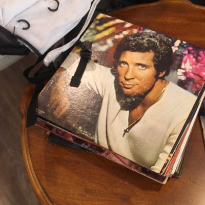 Tom Jones vinyl record album resting on a stack of records, displayed on a wooden side table alongside a PlayStation 4 game.
